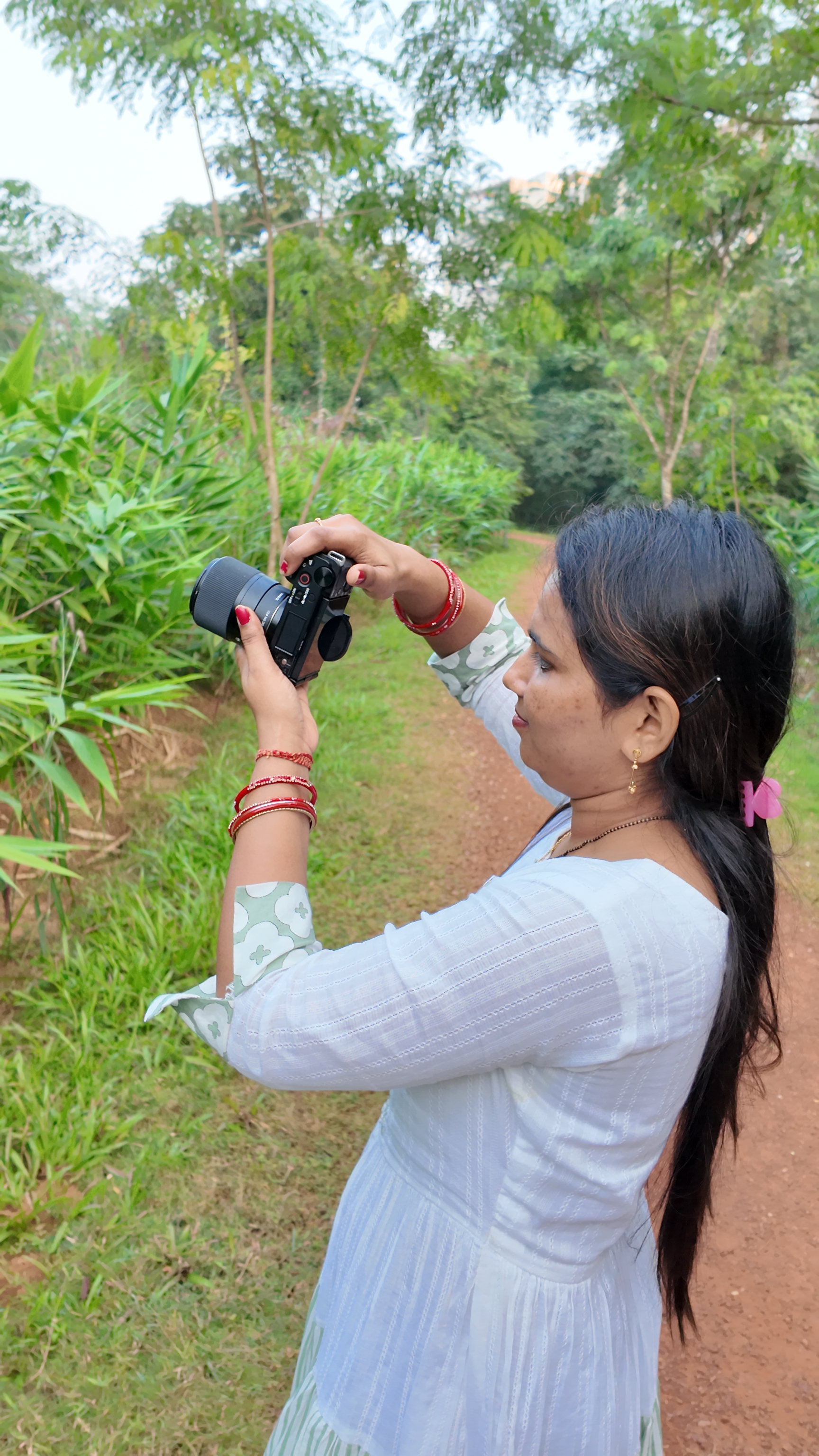 Rasmita holding a camera, photographing the trees at Anandabana