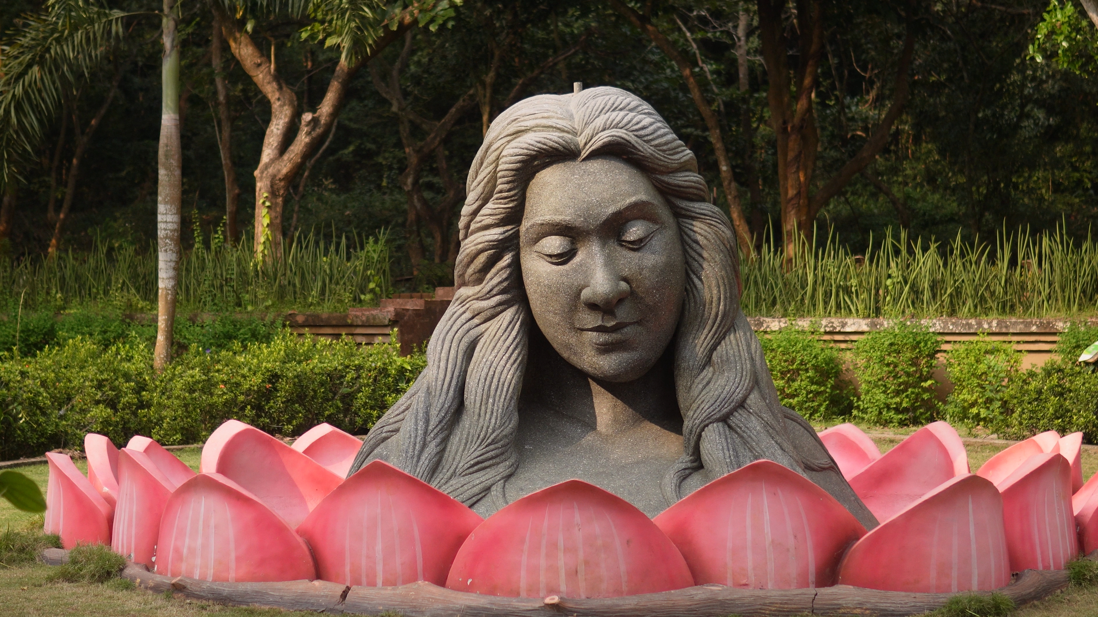 Large sculpture of a woman's face emerging from a lotus flower at the Medicinal Garden